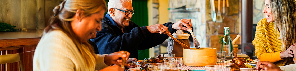 Foto de una pareja de abuelos disfrutando una cena familiar con su familia